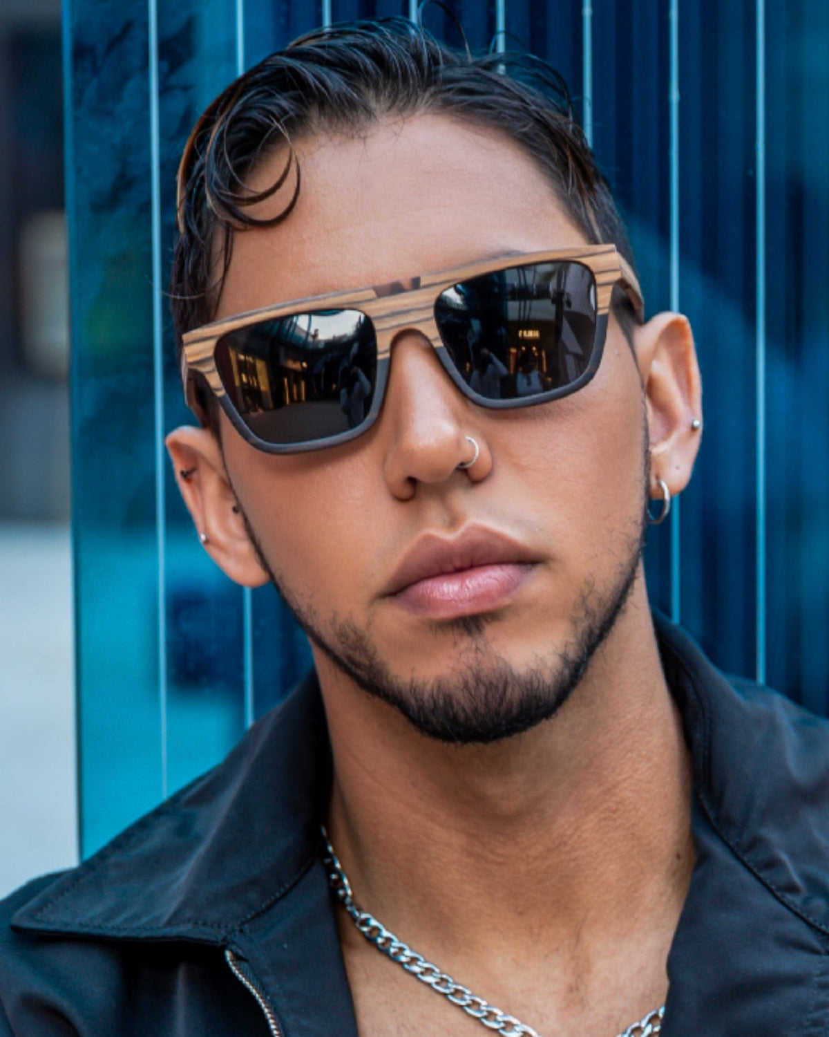 Man wearing sunglasses and a black jacket with a blue background